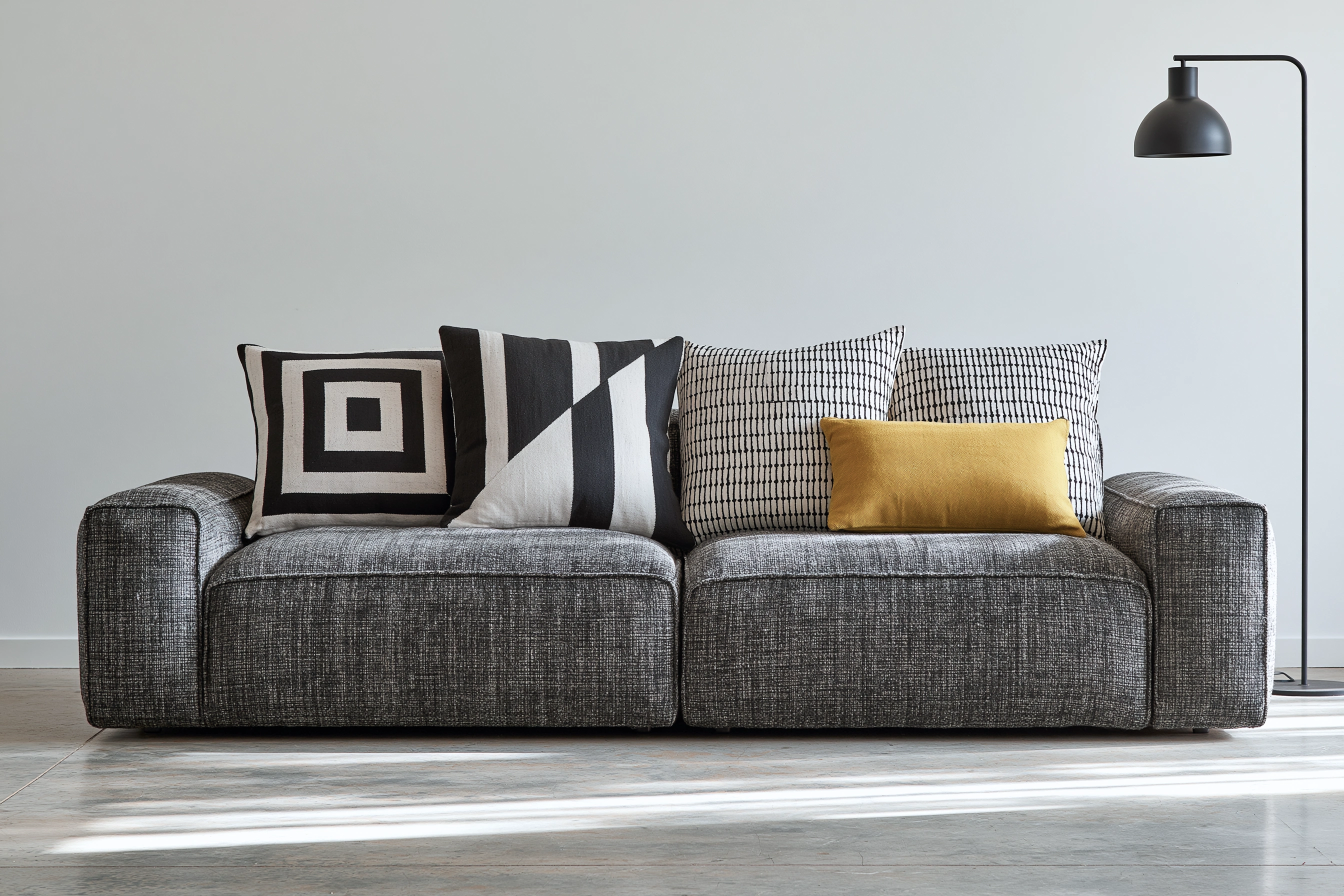 Bold graphic black-and-white cushions with a single yellow, pattern carrying the set.
