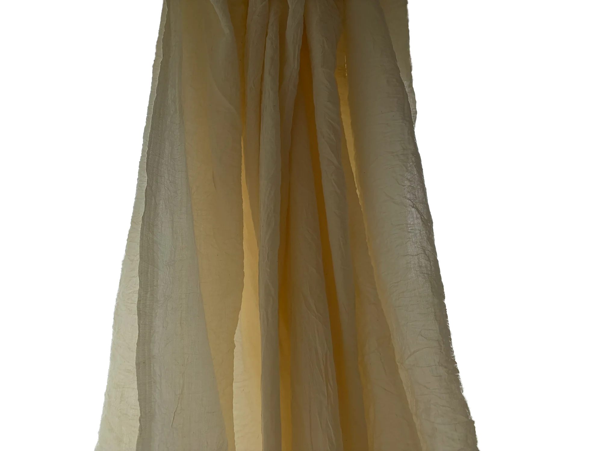 A panel of warm gold sheer curtain, lit from behind and falling in soft folds.